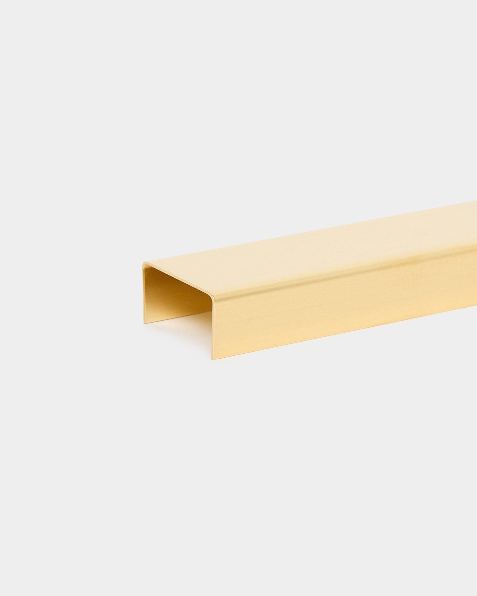 The Liva | Cover / Brass, 120 cm by WoodUpp is a gold-toned U-shaped metal trim accessory for acoustic wood panels, displayed against a light background.