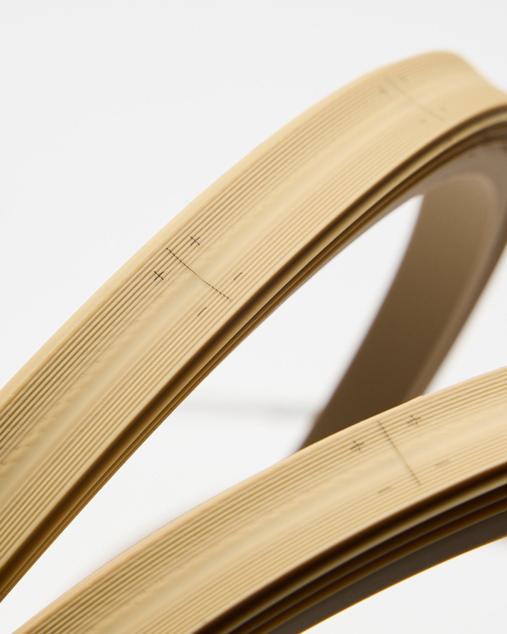 Close-up of two beige WoodUpp Lumi LED striplights, 240 cm each, featuring fine lines and markings, displayed against a plain white background.