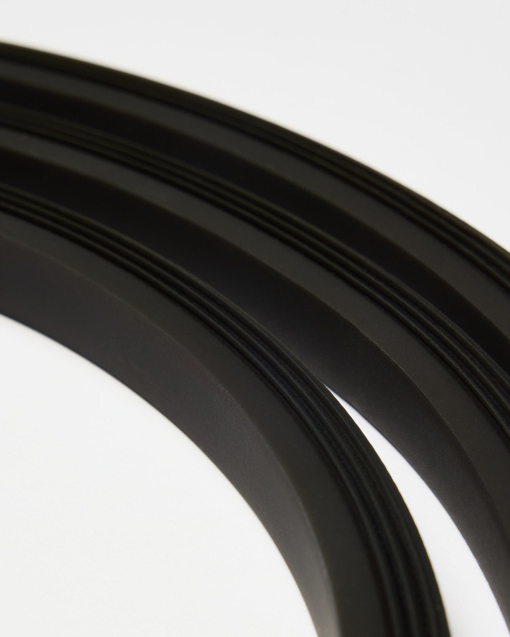 Close-up of the black Lumi LED striplight by WoodUpp (300 cm), arranged in curved lines on white, complementing the minimalist Akupanel acoustic panel style.