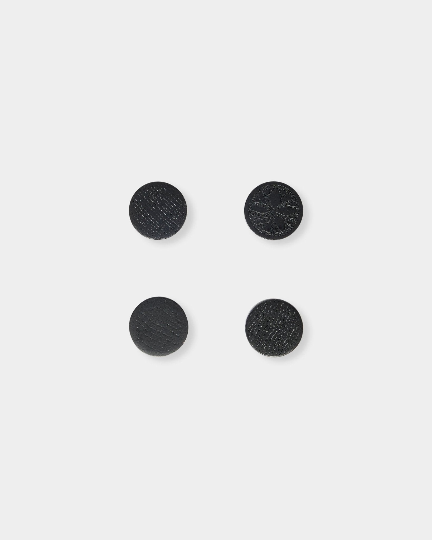 Set of four black oak Norr magnets by WoodUpp, neatly arranged in a square on a plain light gray background.