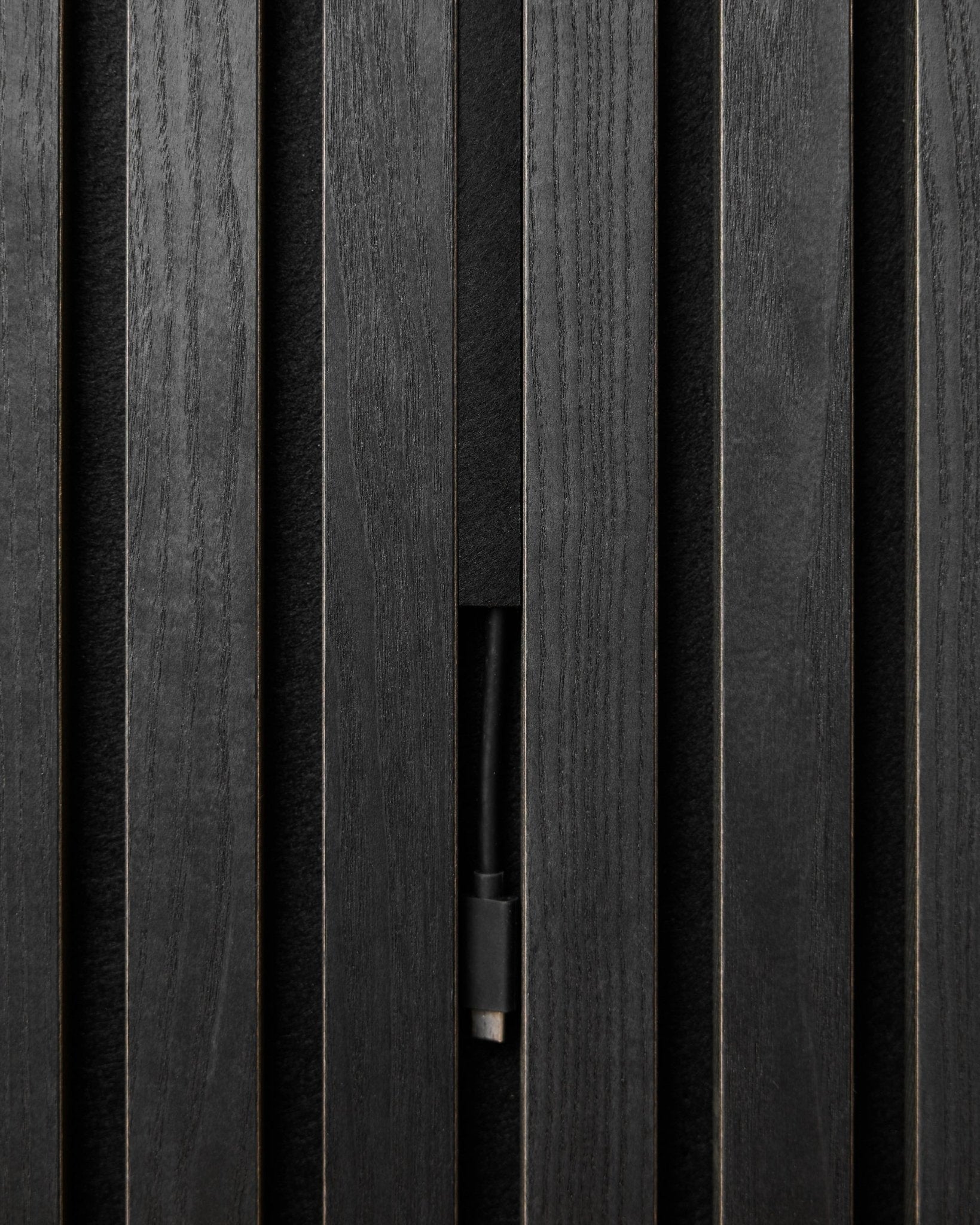 Black WoodUpp Pop-on Cable Covers (3 pcs) conceal cables neatly behind Akupanel acoustic wood panels, maintaining a clean, seamless Nordic look.