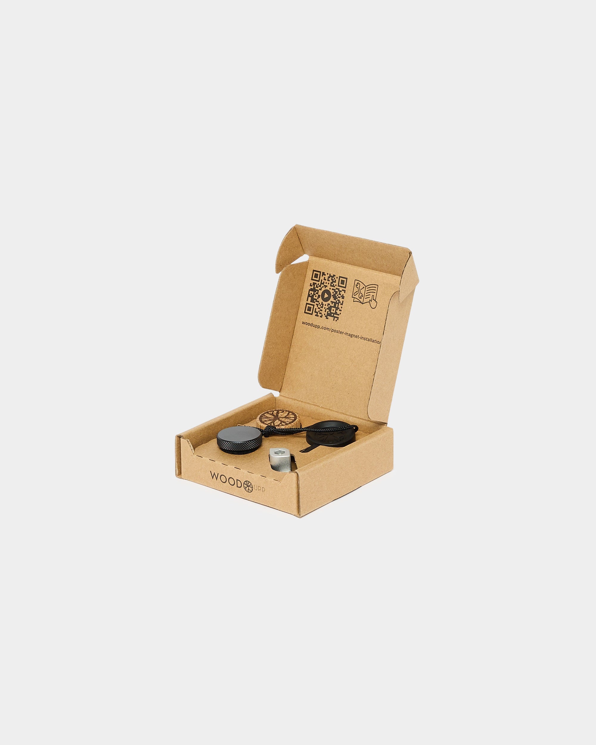 Open cardboard box with round and rectangular black and silver Akupanel accessories inside, on white background; visible QR codes and product information text.