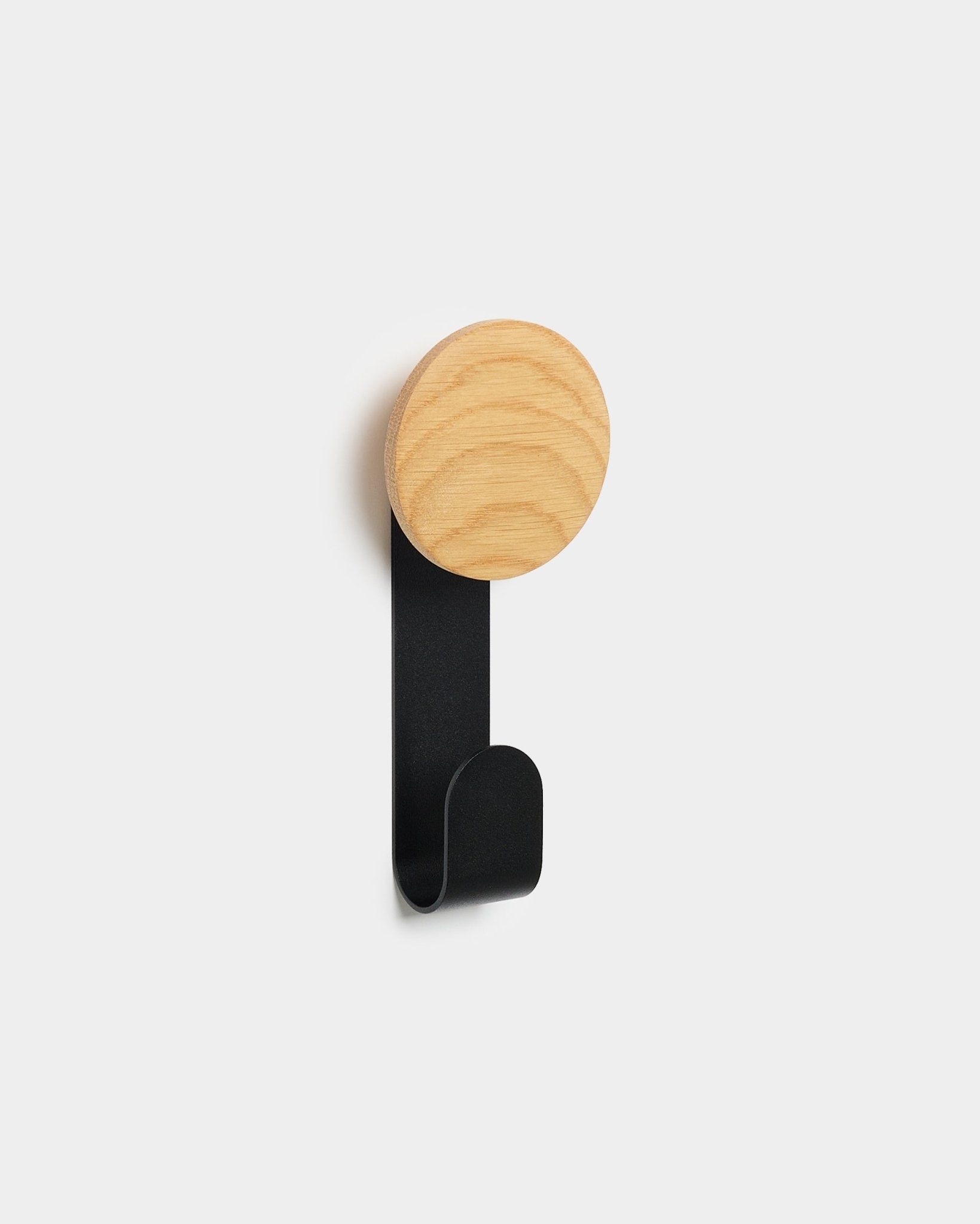 The Linn Vertical Hanger by WoodUpp with a round natural oak top and black metal hook, designed to hang accessories on Akupanels Nordic acoustic wood panels.
